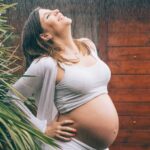 Femme enceinte tenant son ventre, représentant l'accompagnement des femmes en santé et bien-être.