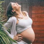 Femme enceinte tenant son ventre, représentant l'accompagnement des femmes en santé et bien-être.